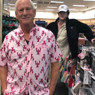 The father is wearing a lobster shirt while the son is standing in the background.